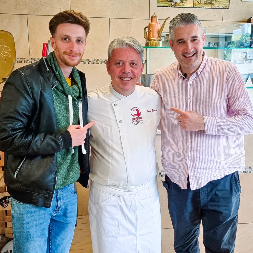 Vincenzo Esposito, owner of Pizzeria Carmnella, stands smiling between 2 Vincenzos inside his restaurant. Widely recognized for serving some of the best Neapolitan pizza in the world.